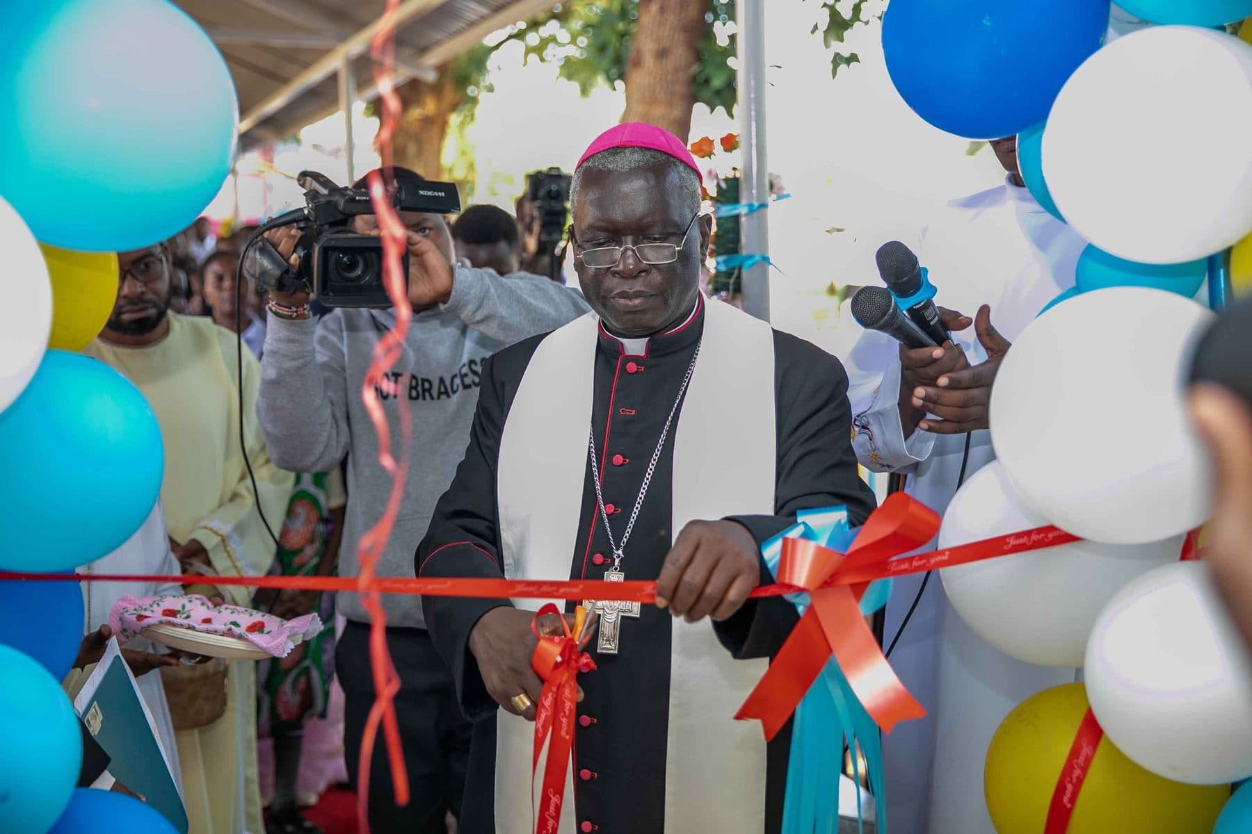 Archbishop Philip Anyolo cuts the ribbon to open the Mother and Child Centre